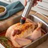 Cajun injector filled with marinade being used on turkey