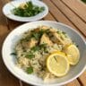 Greek chicken and lemon rice recipe on white plate with lemon and herbs